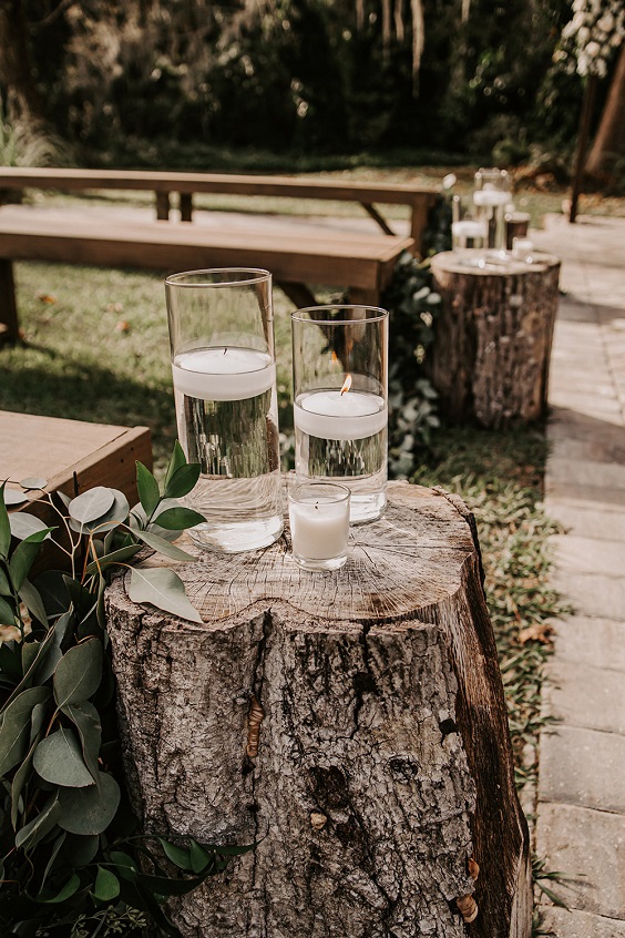 candles on wooden stump as wedding aisle chairs decoration  for rustic themed wedding colors for 2025 sage green and slate blue