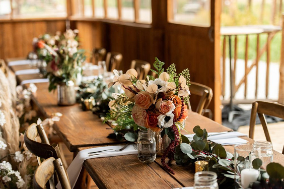wooden table with terracotta and orange flowers centerpieces for rustic themed wedding colors for 2025 terracotta and orange