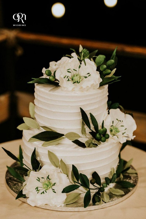 white wedding cake dotted with dark green leaves for navy blue wedding colors for 2025 navy blue dark green and white