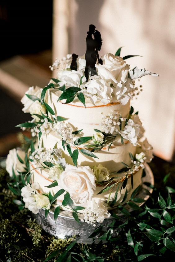 white wedding cake dotted with white flowers and greenery for navy blue wedding colors for 2025 navy blue white and gold