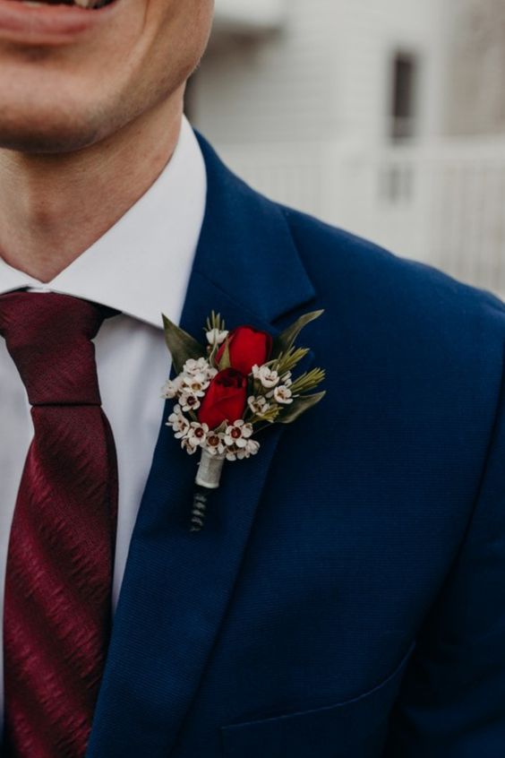 navy blue grooms attire with a wine tie and red flowers for blue wedding colors combos for 2025 navy blue and red