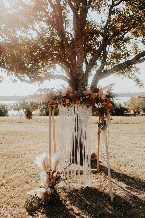 ceremony arch decorated with burgundy and burnt orange flowers and greenery for burgundy wedding colors for 2025 burgundy and burnt orange
