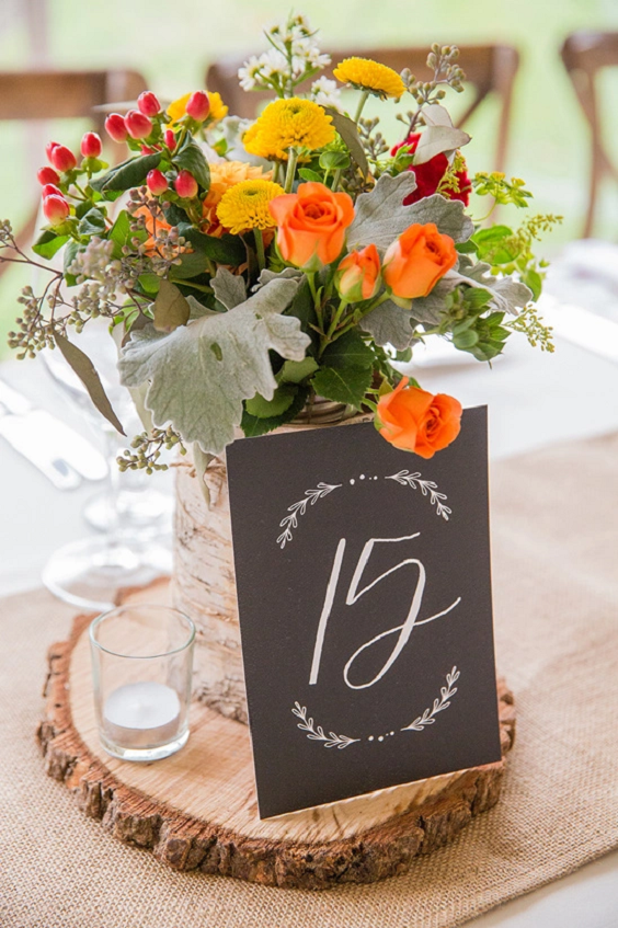 yellow red and orange flowers behind table number for may wedding colors combos for 2025 orange and yellow