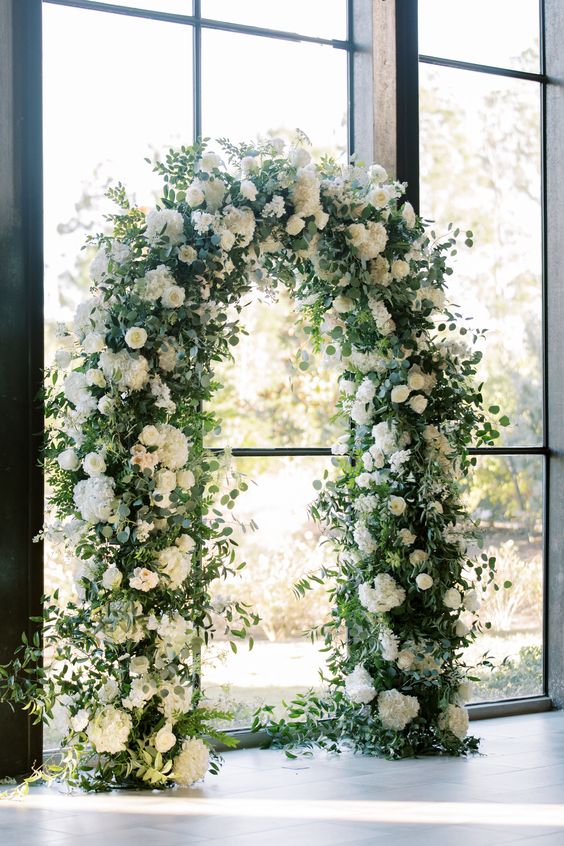 wedding arch with white flowers and greenery for april wedding colors combos for 2025 dark green and white