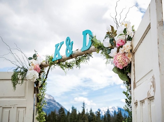 wedding arch with dusty rose and white flowers and teal letters for teal wedding colors for 2025 teal dusty rose and blush