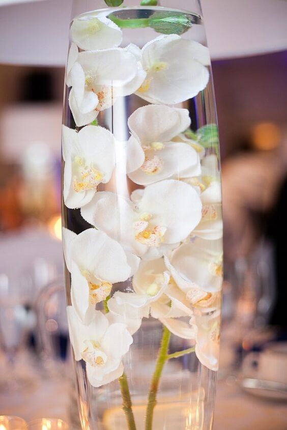 white flowers in glass bottle centerpiece for summer royal blue wedding