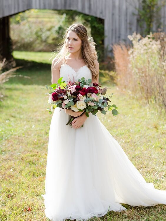 bride with bouquet for fall burgundy wedding